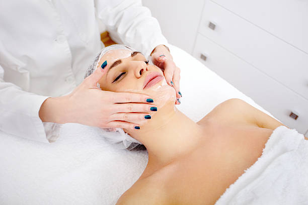 A young woman is getting a facial treatment.